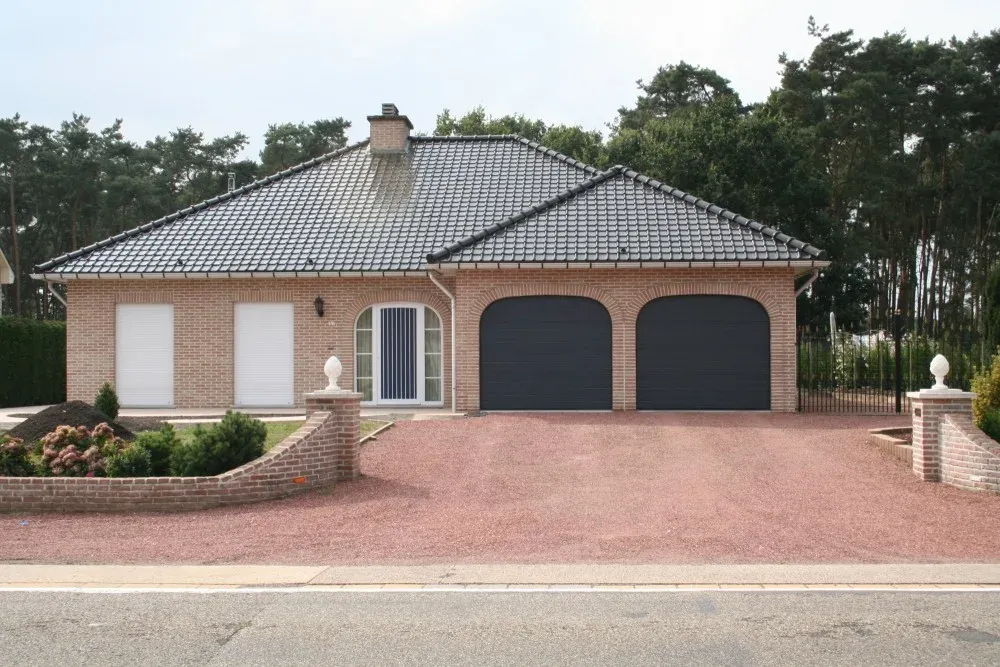Twee donkergrijze garagepoorten bij een bungalow