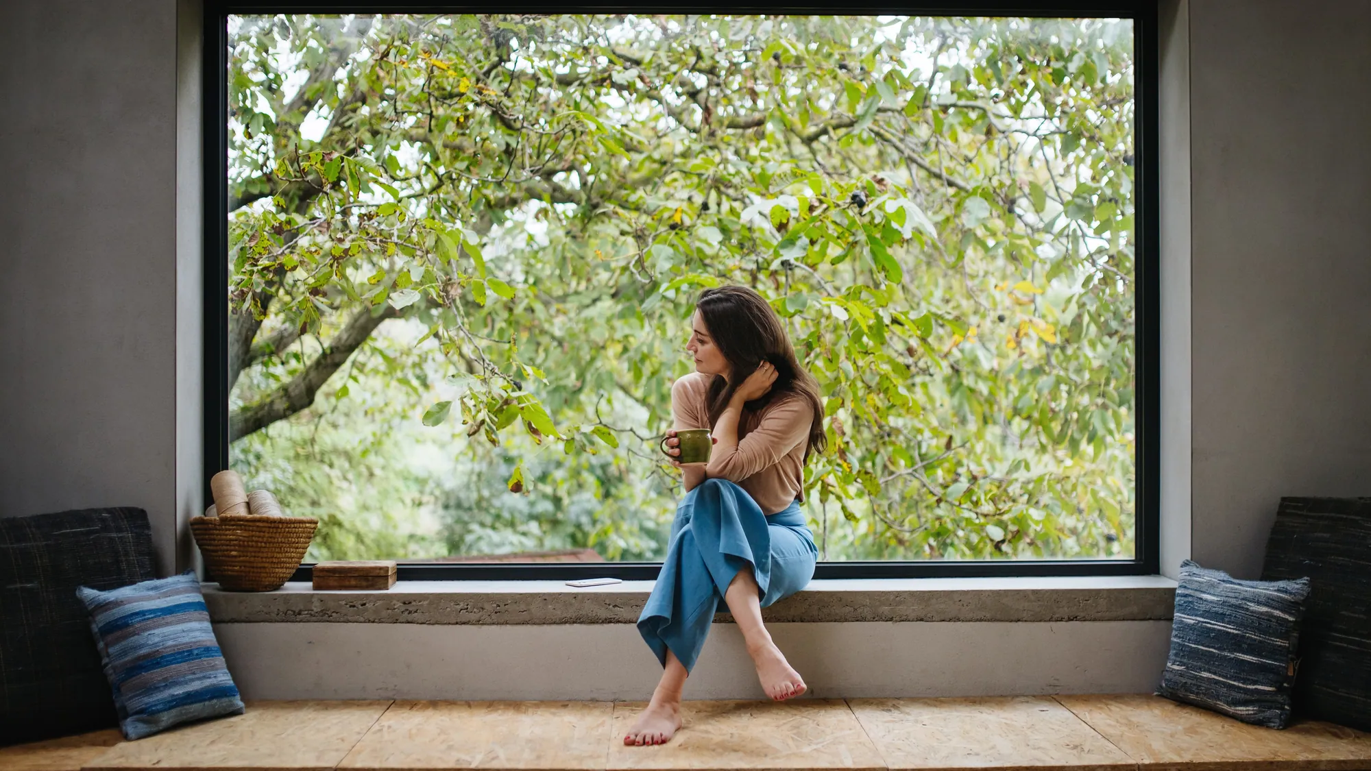 Vrouw zit in een groot vast raam met uitzicht op het groen