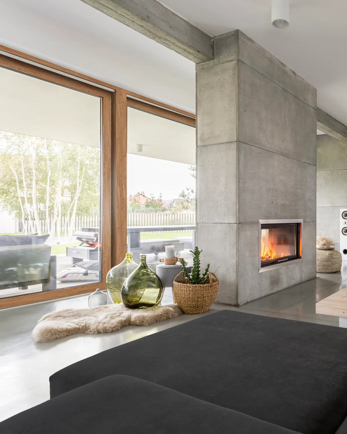 Woonkamer met grote schuiframen in houtkleur en open haard