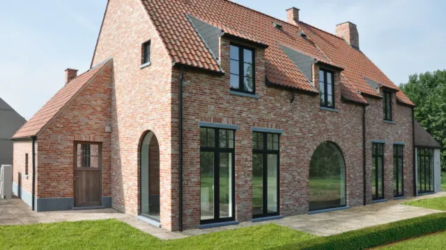 Landelijke woning in rode baksteen met zwarte ramen en boogramen